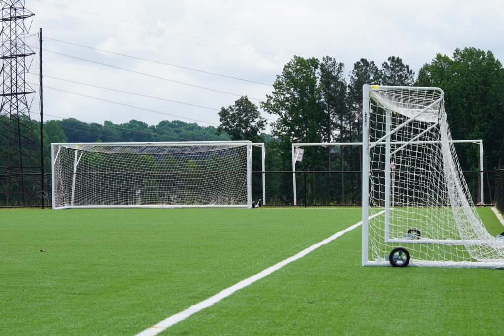three white goal nets on grass field